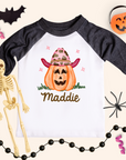 Halloween-themed children's shirt with a pumpkin design and name 'Maddie', surrounded by Halloween decorations.