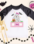 Halloween-themed children's shirt with ghost design and name 'Emma', surrounded by Halloween decorations.
