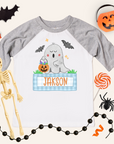Halloween-themed children's shirt with ghost design and name 'Jakson', surrounded by Halloween decorations.