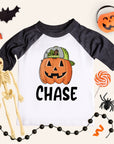 Children's Halloween-themed shirt with pumpkin design and skeleton, spider, and candy decorations.