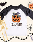 Halloween-themed shirt with pumpkin design and skeleton, spider, and bat decorations on a light background.