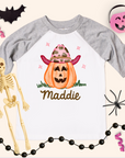 Halloween-themed t-shirt with pumpkin and cowboy hat design, surrounded by Halloween decorations.