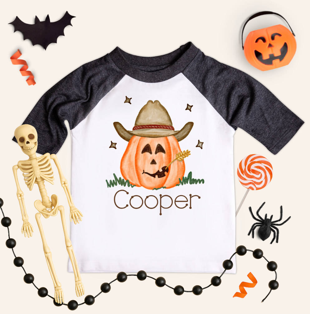 Children&#39;s Halloween-themed shirt with a cowboy pumpkin design and skeleton, lollipop, and spider decorations.