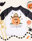 Children's Halloween-themed shirt with a cowboy pumpkin design and skeleton, lollipop, and spider decorations.