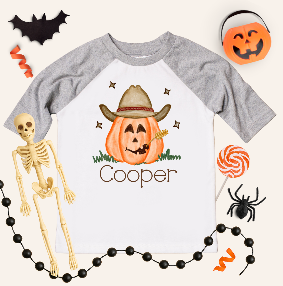 Halloween-themed shirt with a pumpkin wearing a cowboy hat and the name &#39;Cooper&#39;, surrounded by Halloween decorations.