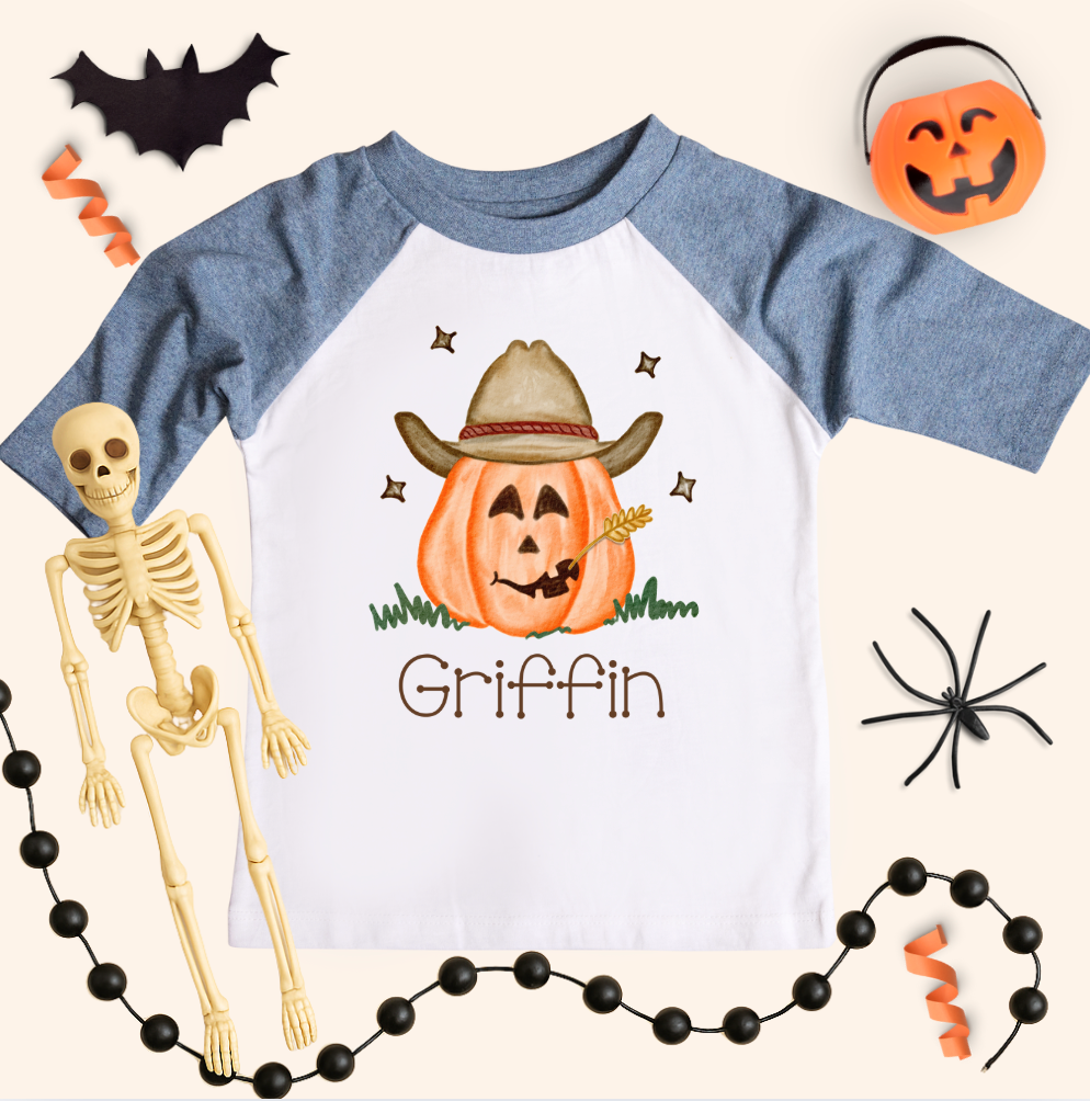 Halloween-themed shirt with a cowboy pumpkin design and skeleton, spider, and pumpkin decorations around.