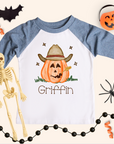 Halloween-themed shirt with a cowboy pumpkin design and skeleton, spider, and pumpkin decorations around.