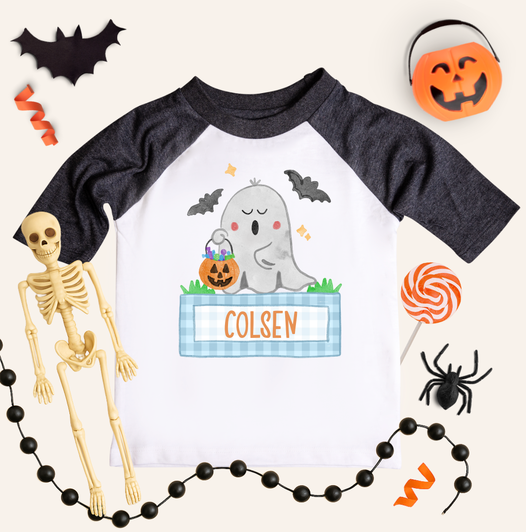 Children's Halloween-themed shirt with ghost design and name 'Colsen', surrounded by Halloween decorations.