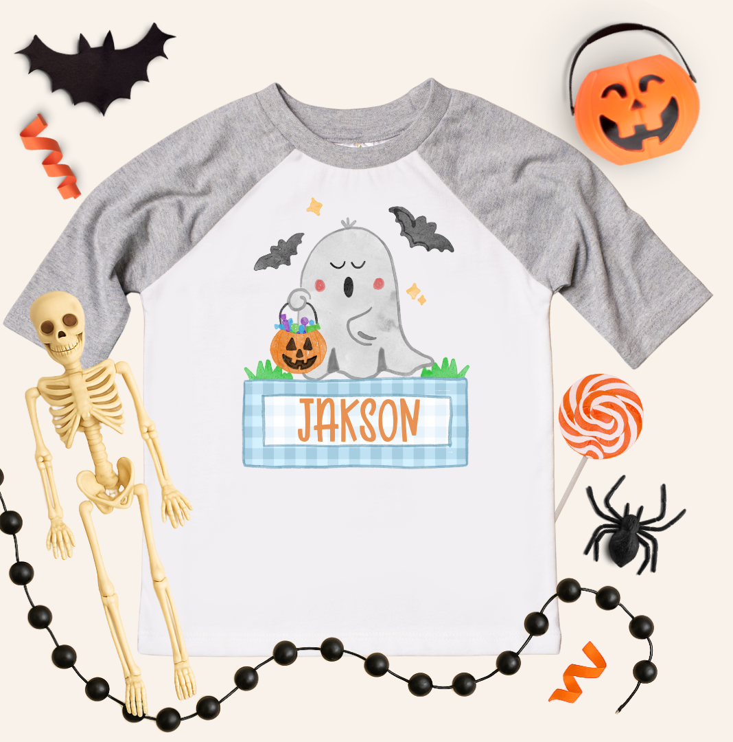 Halloween-themed children's shirt with ghost design and name 'Jakson', surrounded by Halloween decorations.