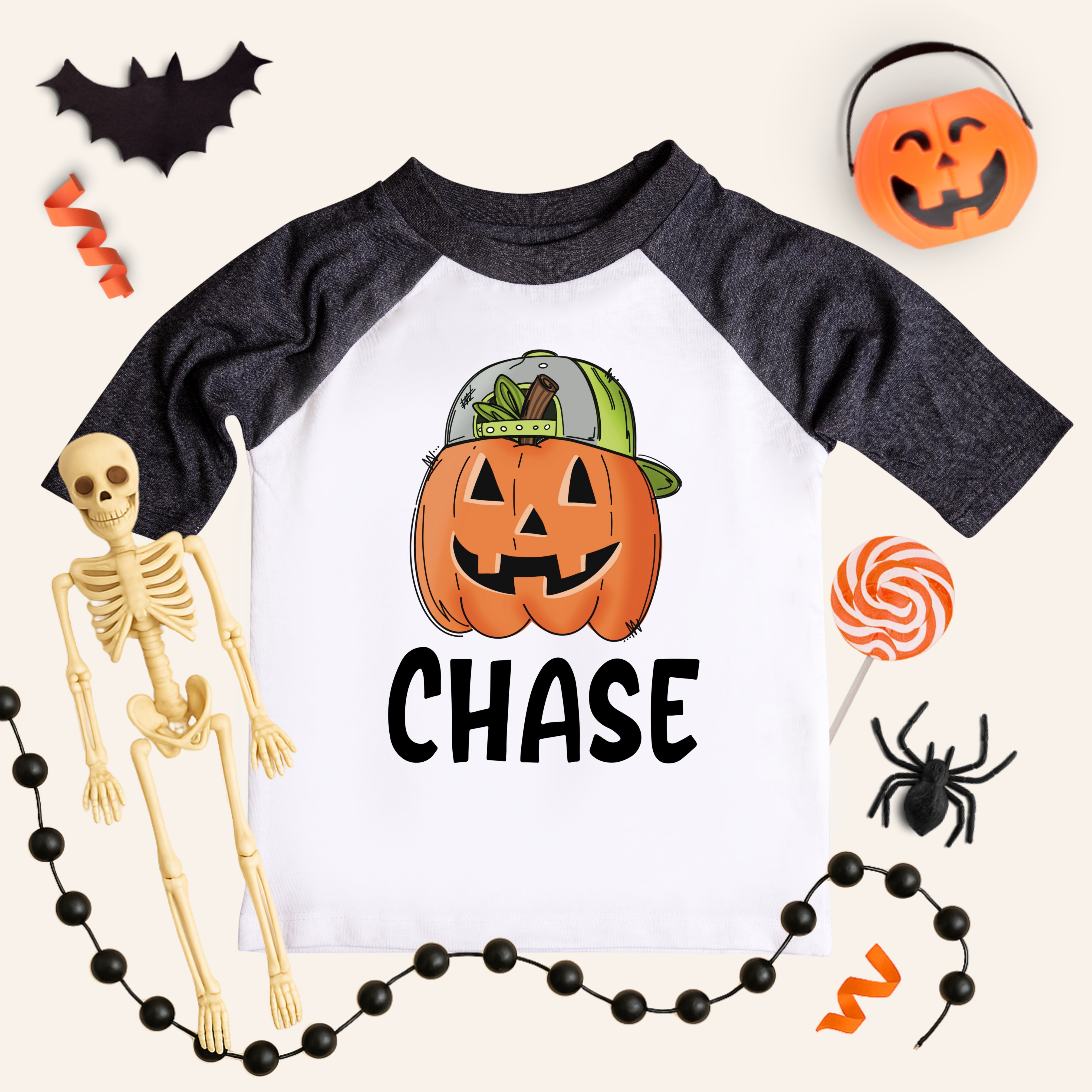 Children's Halloween-themed shirt with pumpkin design and skeleton, spider, and candy decorations.