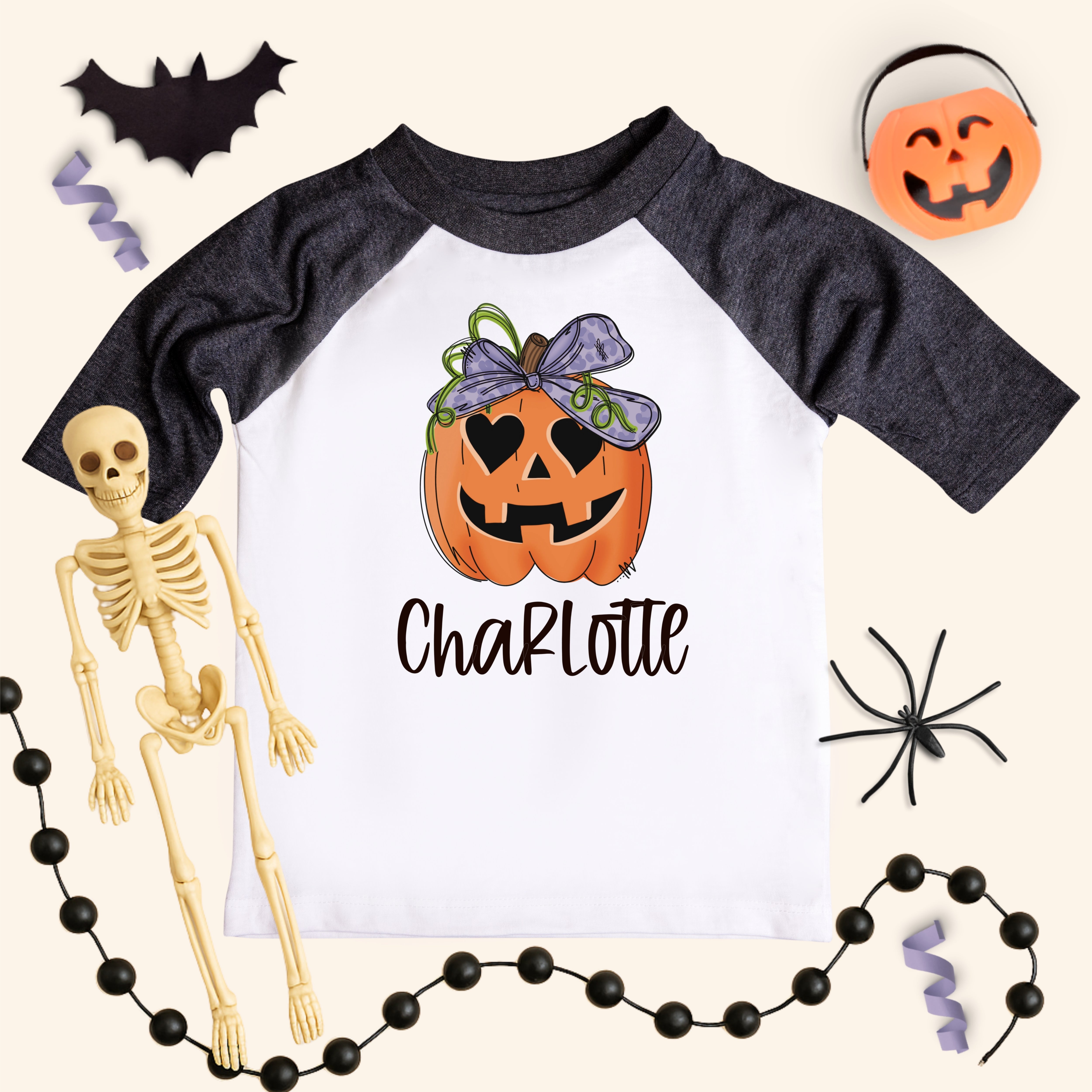 Halloween-themed shirt with pumpkin design and skeleton, spider, and bat decorations on a light background.