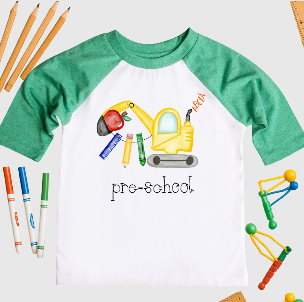 Children's t-shirt with educational graphics and 'pre-school' text, surrounded by school supplies on a white background.
