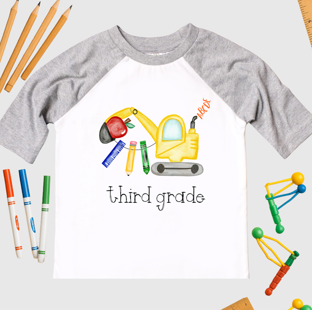 Children's t-shirt with third-grade design featuring an apple and construction-themed elements on a white background.